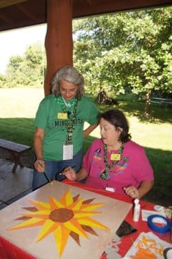 Two adult Girl Scout volunteers gathered over a sunflower painting