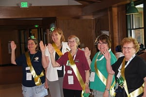 Five RVAA members wearing gold sashes waving at event