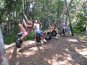Girls on tire swings on the adventure course